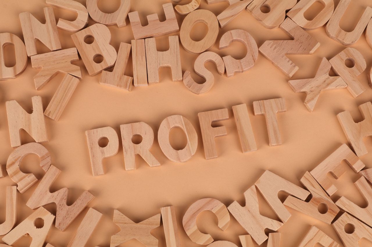 Wooden letters scattered on a table with 'PROFIT' prominently displayed.